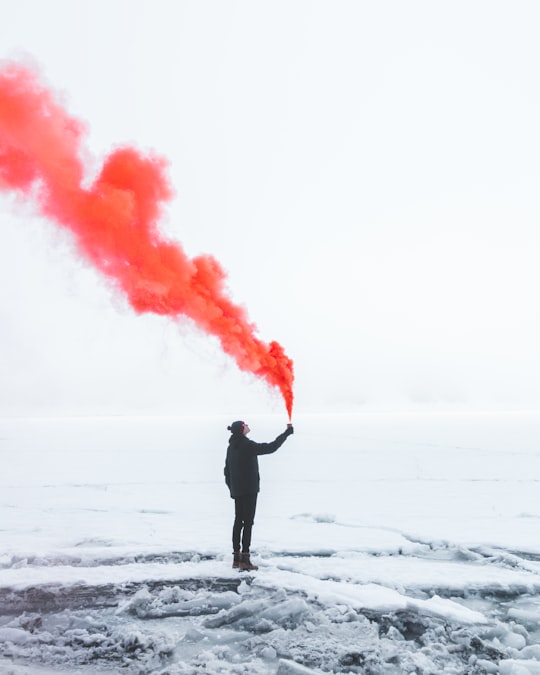 person wearing black jacket and holding red colored smoke flare during daytime in Oeschinen Lake Switzerland