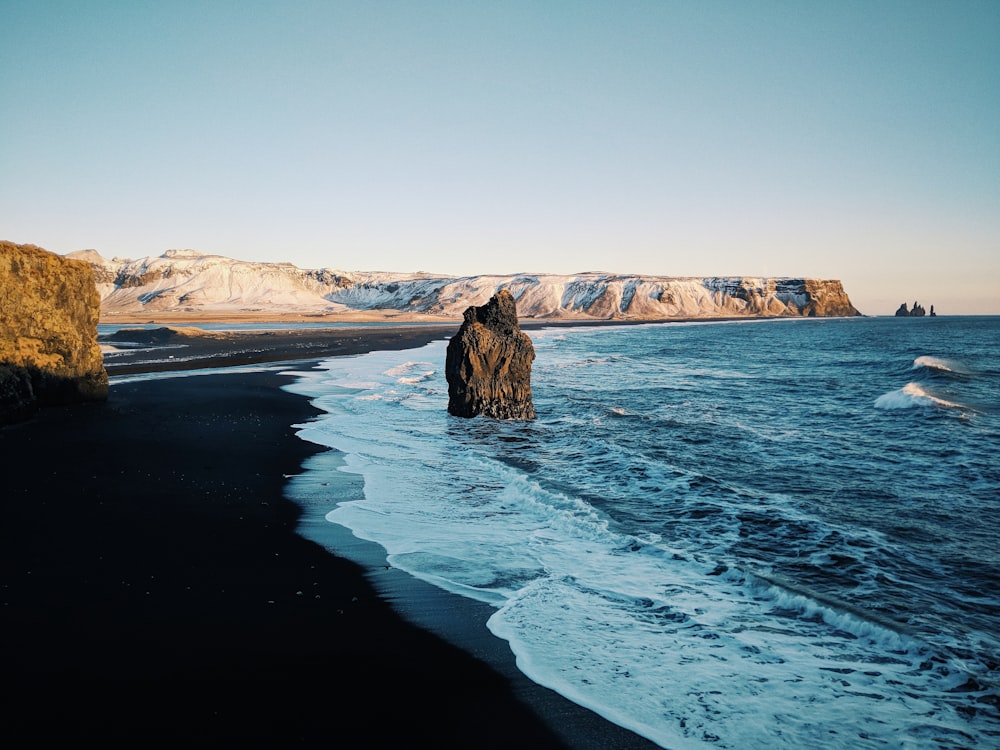 calm beach with rock formation under blue sky at daytime