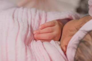 A peaceful sleeping baby wrapped in soft pastel blankets.