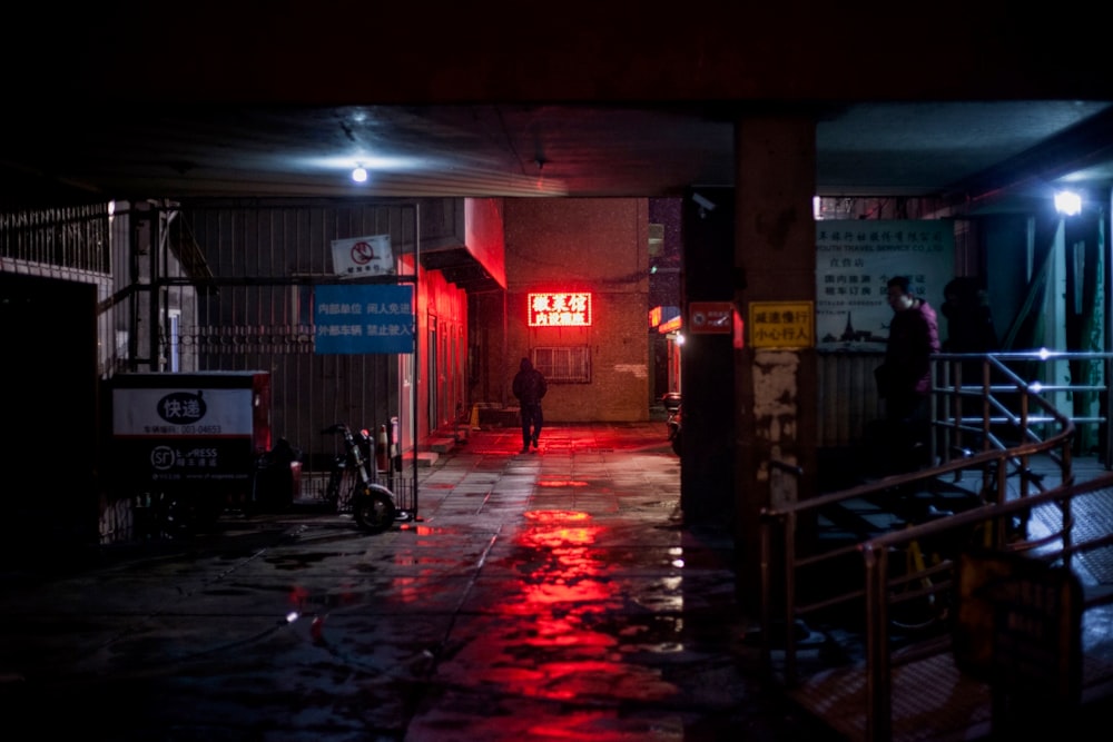 a person walking down a wet sidewalk at night