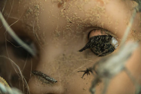 Close-up of a creepy, cracked doll face in a dark room.