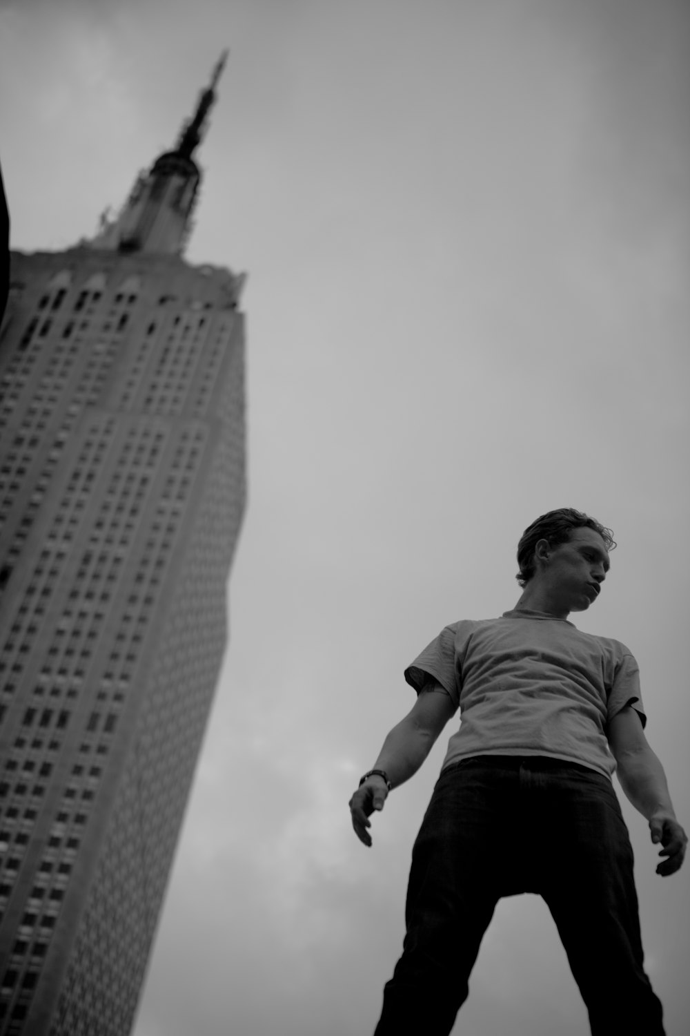 grayscale low-angle photo of man standing near building