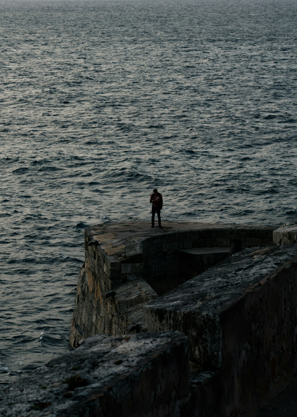 homem em pé no penhasco perto dos corpos de água
