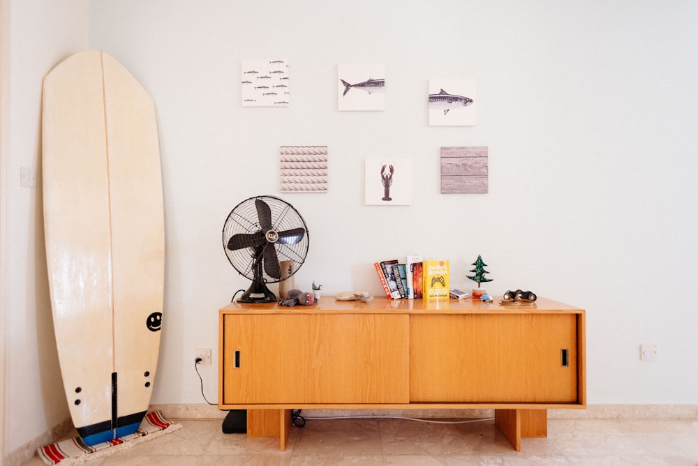 Tabla de surf blanca junto a credenza de madera marrón