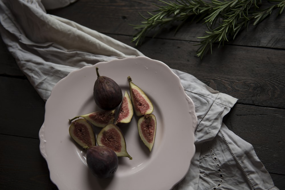 sliced fruit on plate beside green leaves