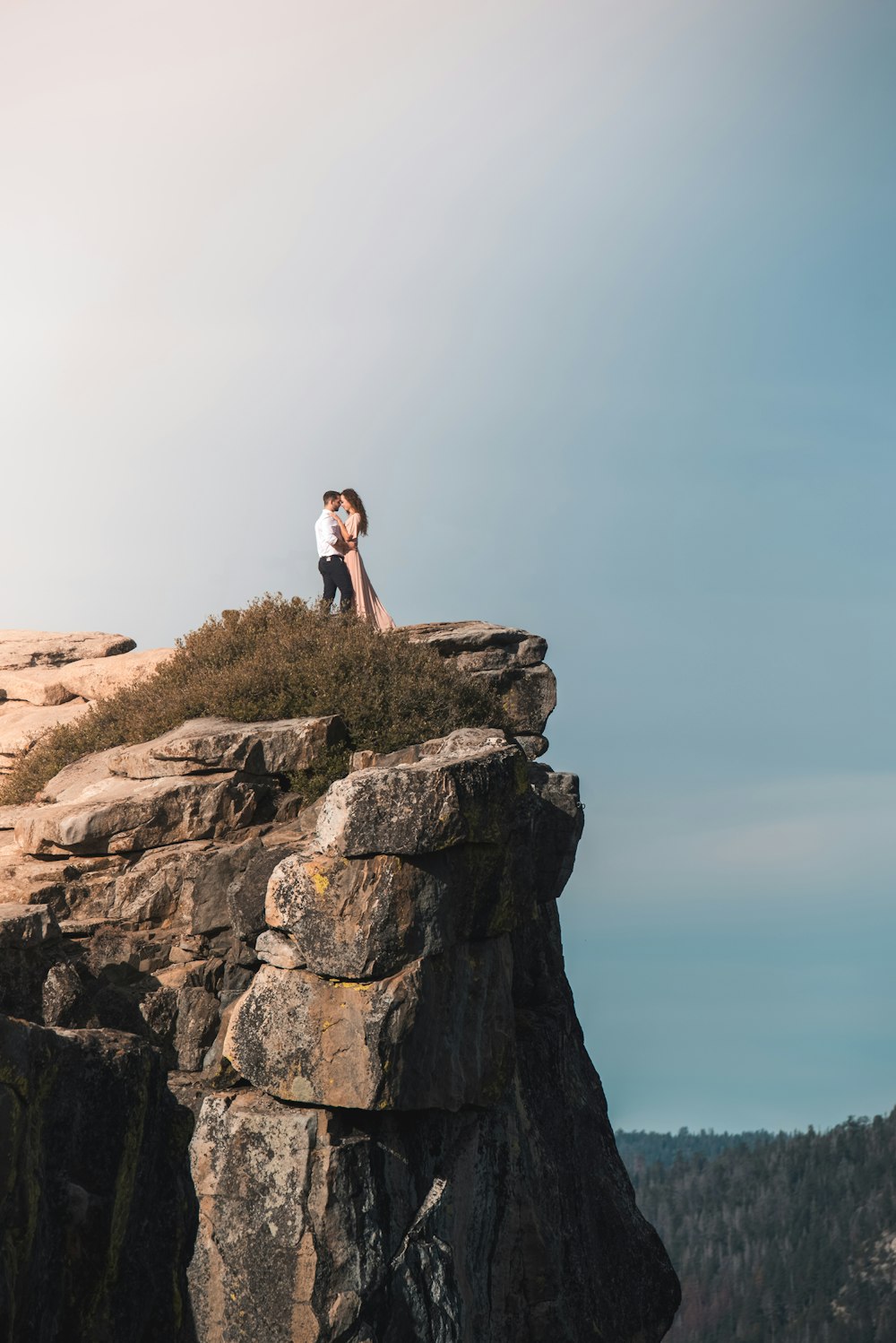 man and woman standing on rock cliff