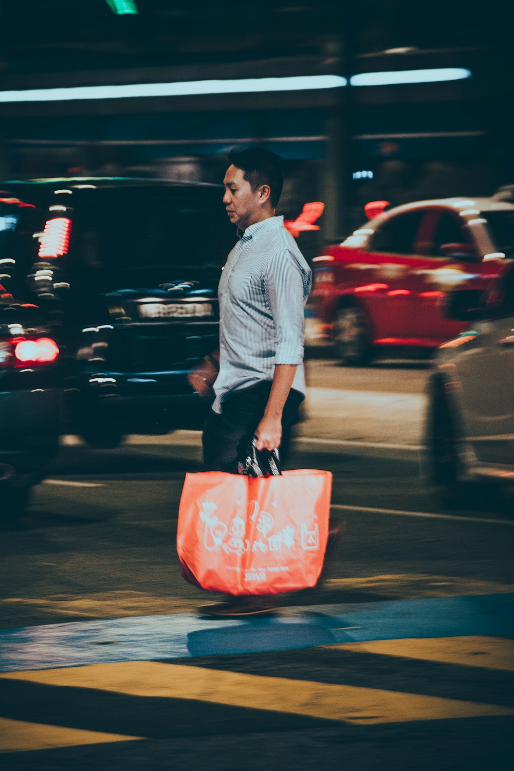 timelapse photo of man walking across in the street with running vehicles