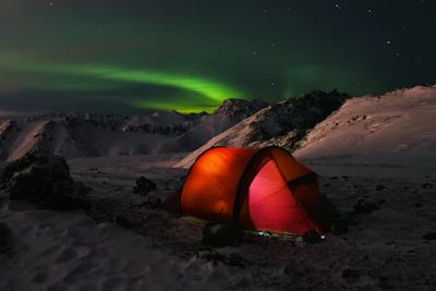The team setting up camp on the frozen Antarctic plateau at dusk with colorful tents.