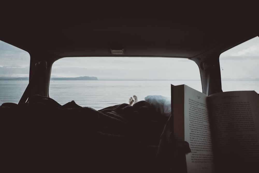 personne lisant un livre à l’intérieur de l’intérieur du véhicule
