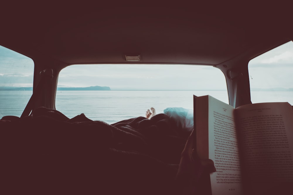 person reading book inside vehicle interior