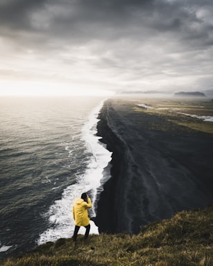 balance and symmetry for photo composition,how to photograph my favourite view in iceland.  the never ending volcanic black beach is absolutely breathtaking in person.; man on top hill near body of water