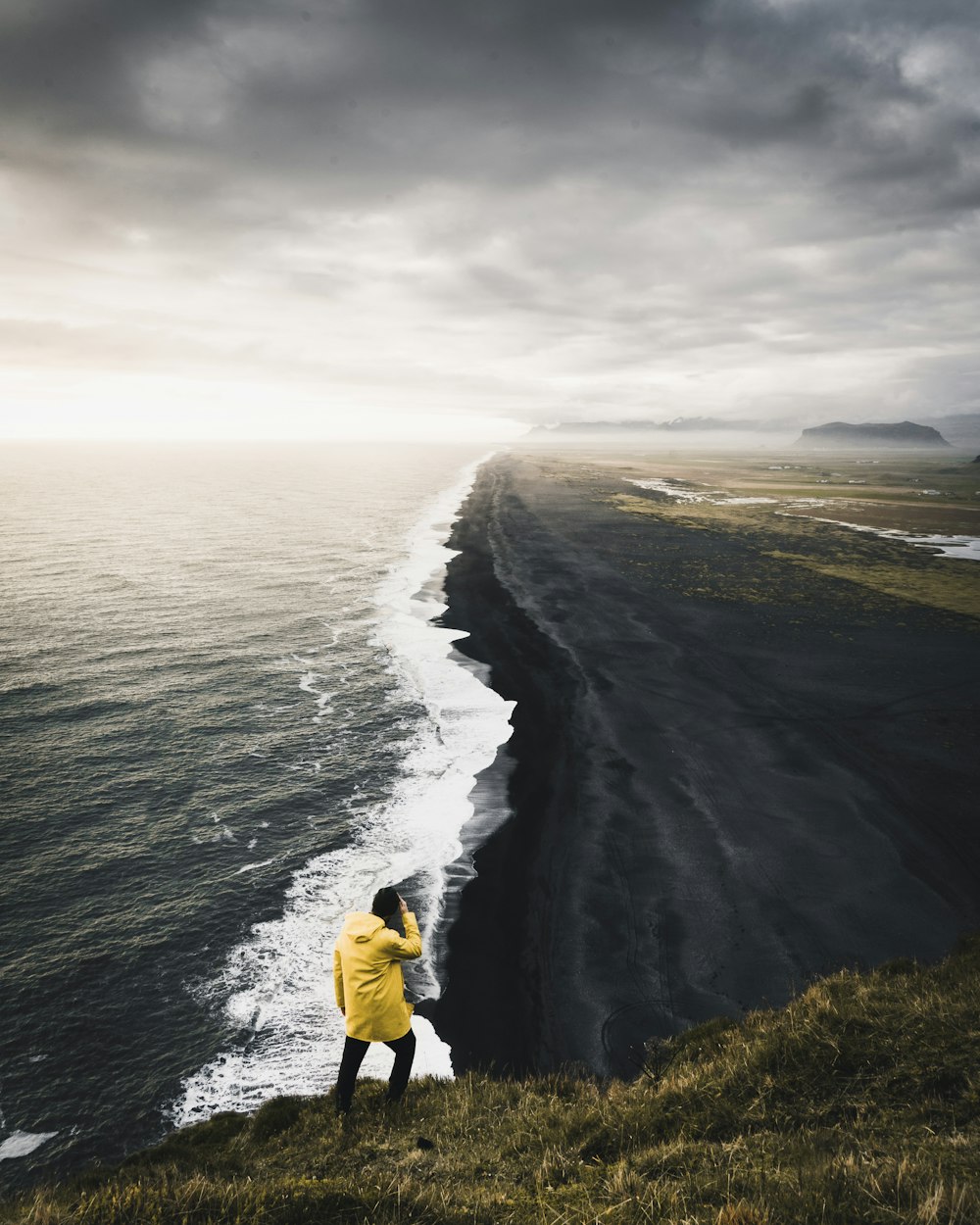 man on top hill near body of water