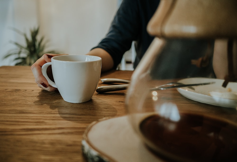 white ceramic mug on brown table in white room