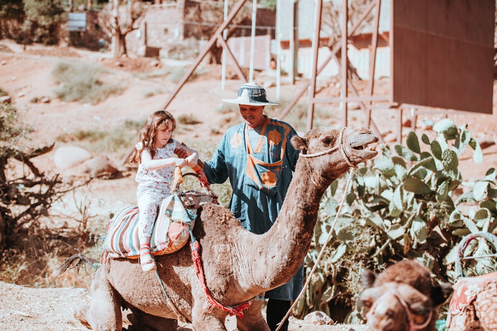 girl riding on brown camel during daytime