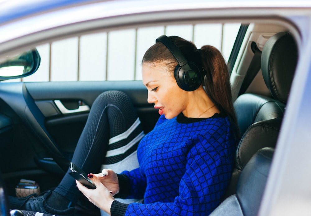 mulher usando fones de ouvido dentro do veículo durante o dia