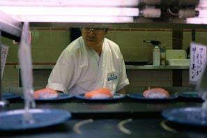 Chef preparing sushi behind a clean counter in bright kitchen