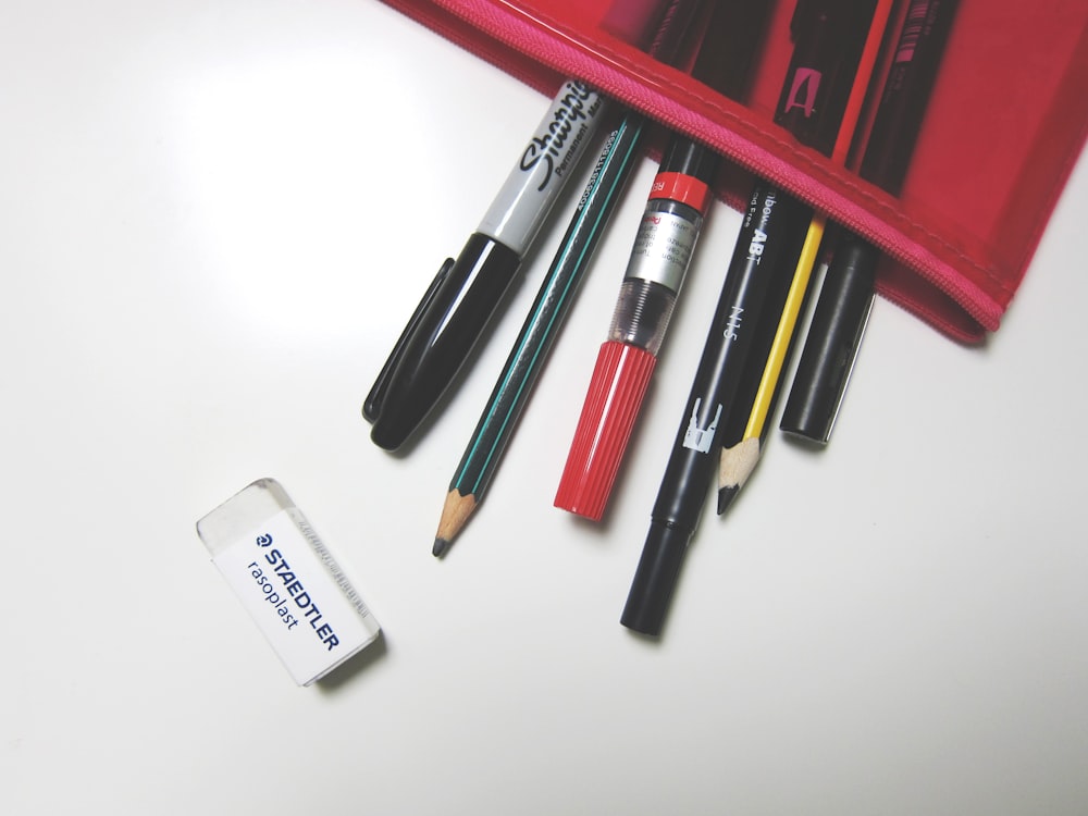 stylo rouge et noir sur surface blanche