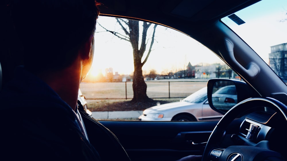 Mann sitzt im Auto und schaut in die Sonne