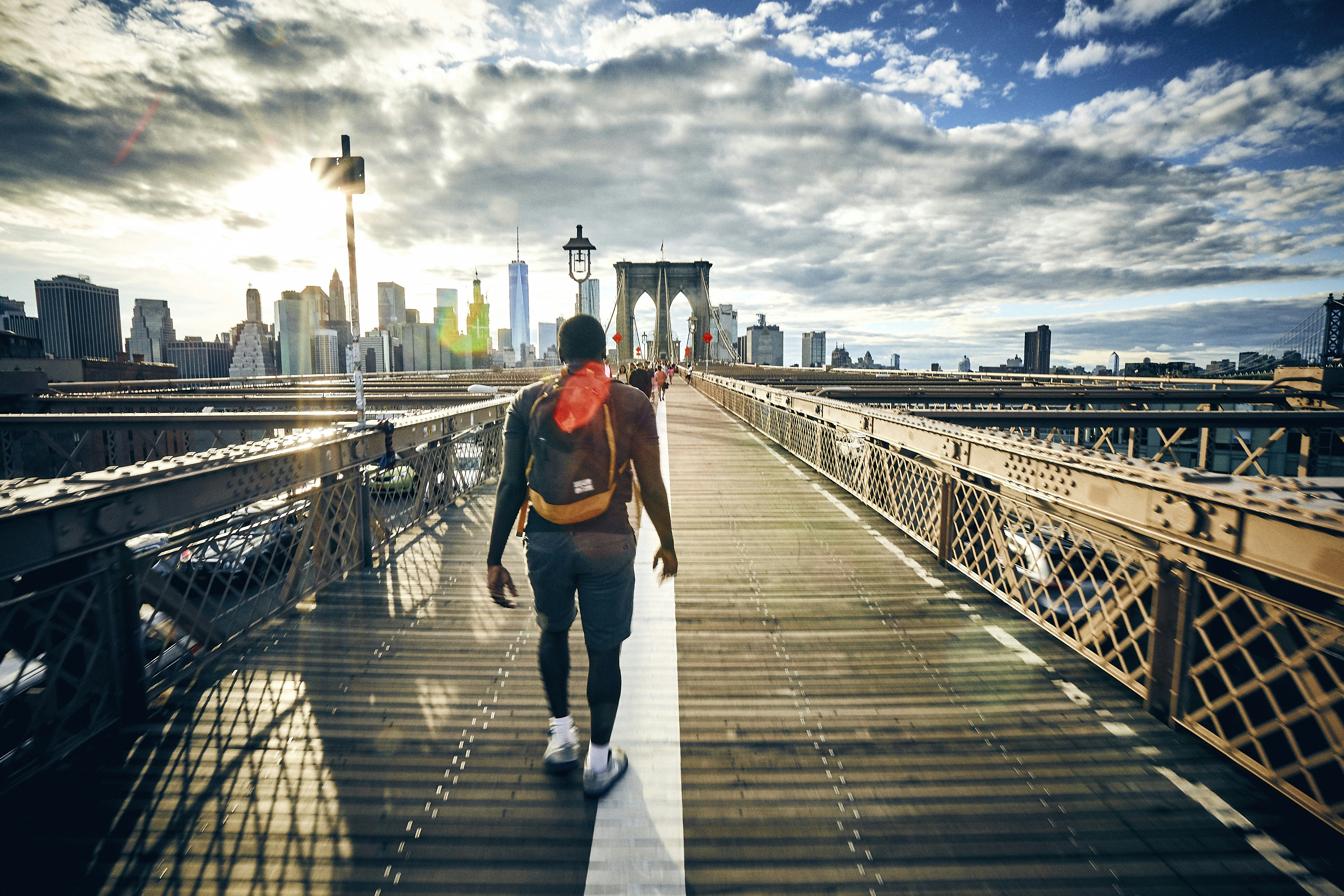 Man walking back from Brooklyn to Manhattan with New York skyline in the background.