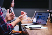 person gesturing during meeting with laptop