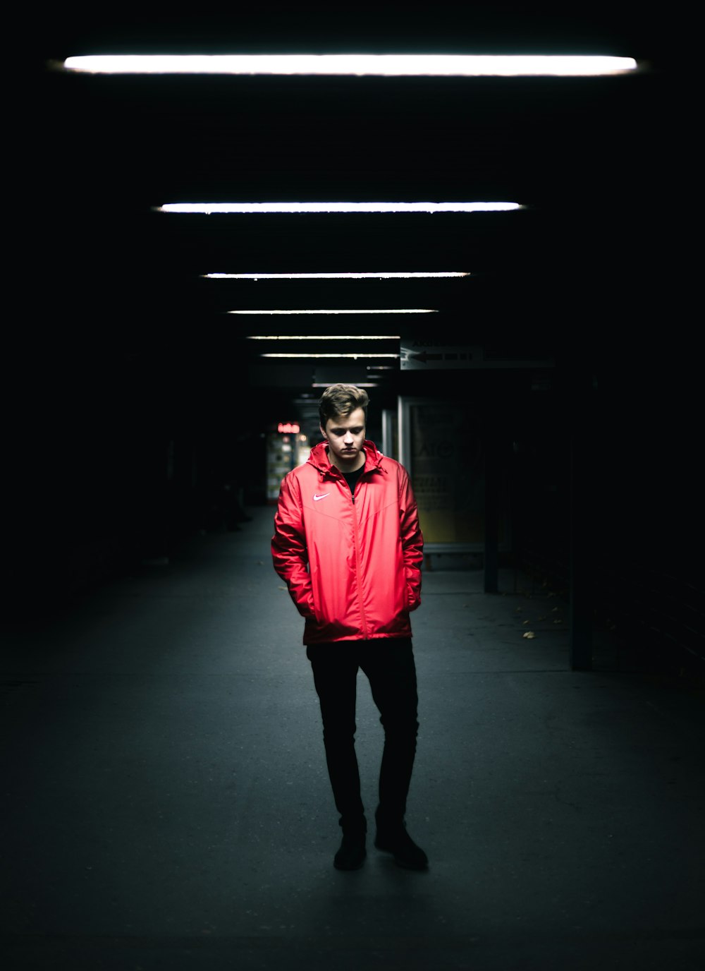 빨간 가죽 재킷을 입은 남자가 어두운 곳에 서 있습니다.