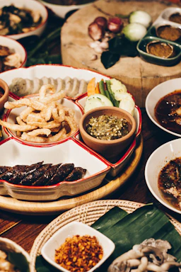 A colorful display of fresh Thai dishes and gourmet sandwiches on rustic wooden table.