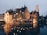 A cozy street in Bruges with medieval buildings lining a calm canal under soft evening light.