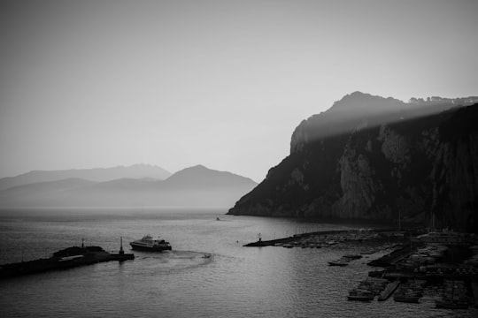 grayscale photo of body of water near mountain in Capri Italy