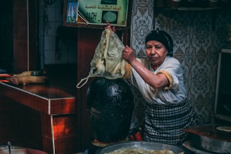 a woman holding a cloth over a pot of food