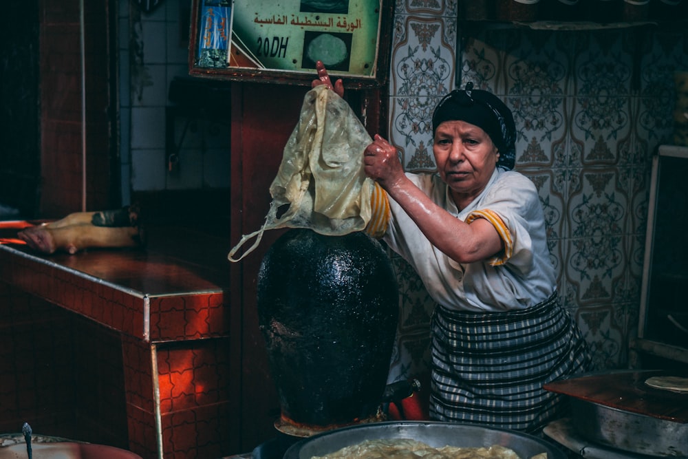 a woman holding a cloth over a pot of food