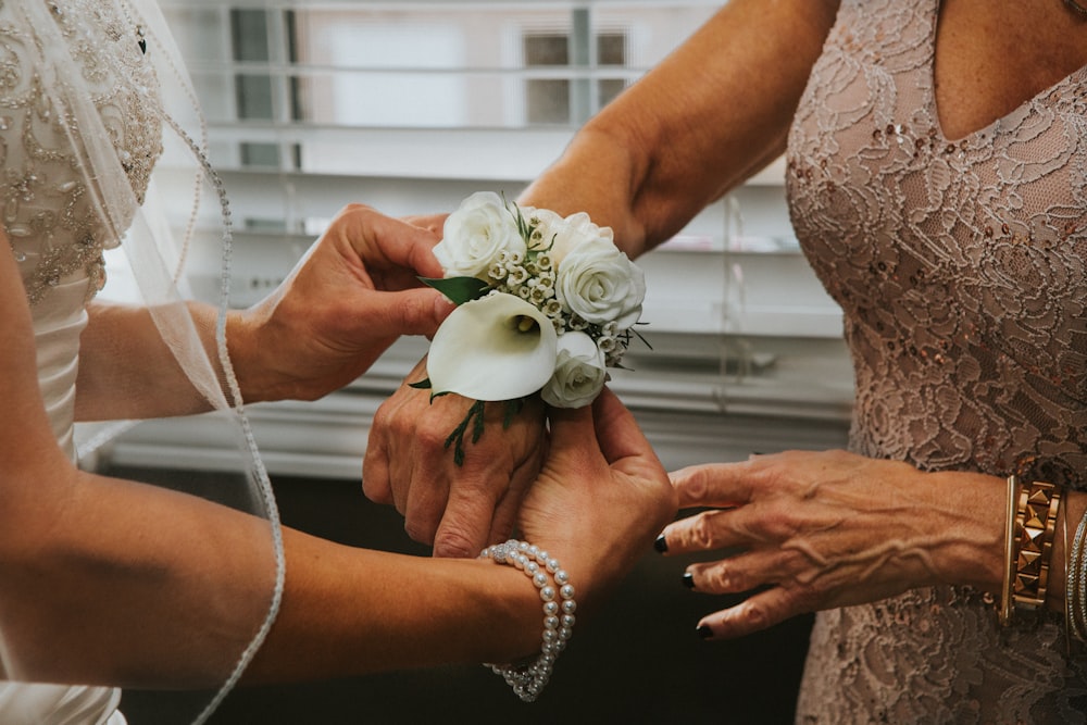 woman put white flowers on woman's hand