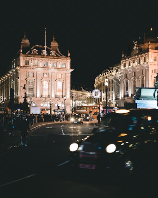 people outside of building with car passing by in Piccadilly Lights United Kingdom
