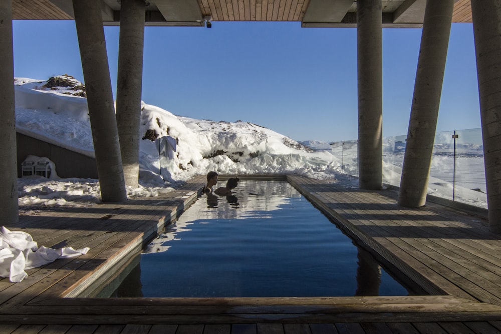 two person taking bath on pool with distance to glacier mountain during daytime