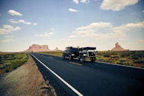 black vehicle towing trailer on black road during daytime