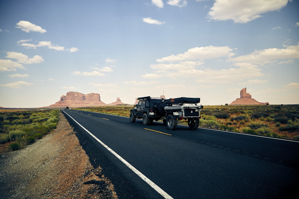 black vehicle towing trailer on black road during daytime