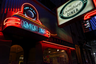 Classic roadside diner sign glowing bright at dusk on a quiet highway stretch
