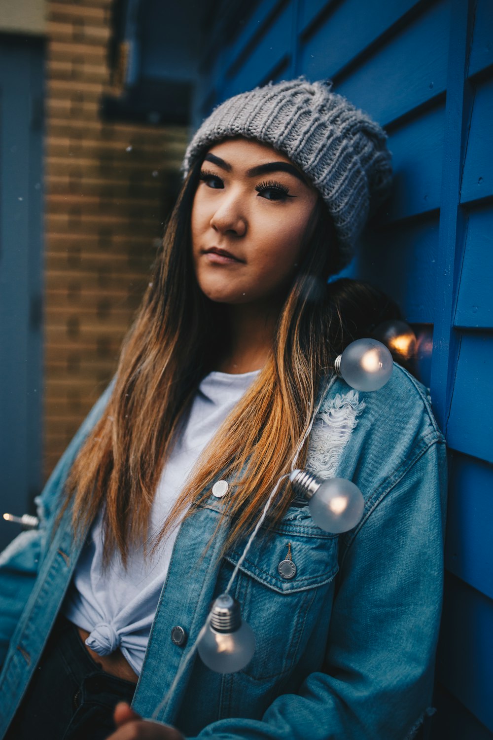 femme porte une casquette en tricot gris s’appuie sur un mur en bois bleu