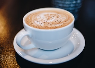 white ceramic teacup on white ceramic saucer filled with coffee in focus photography