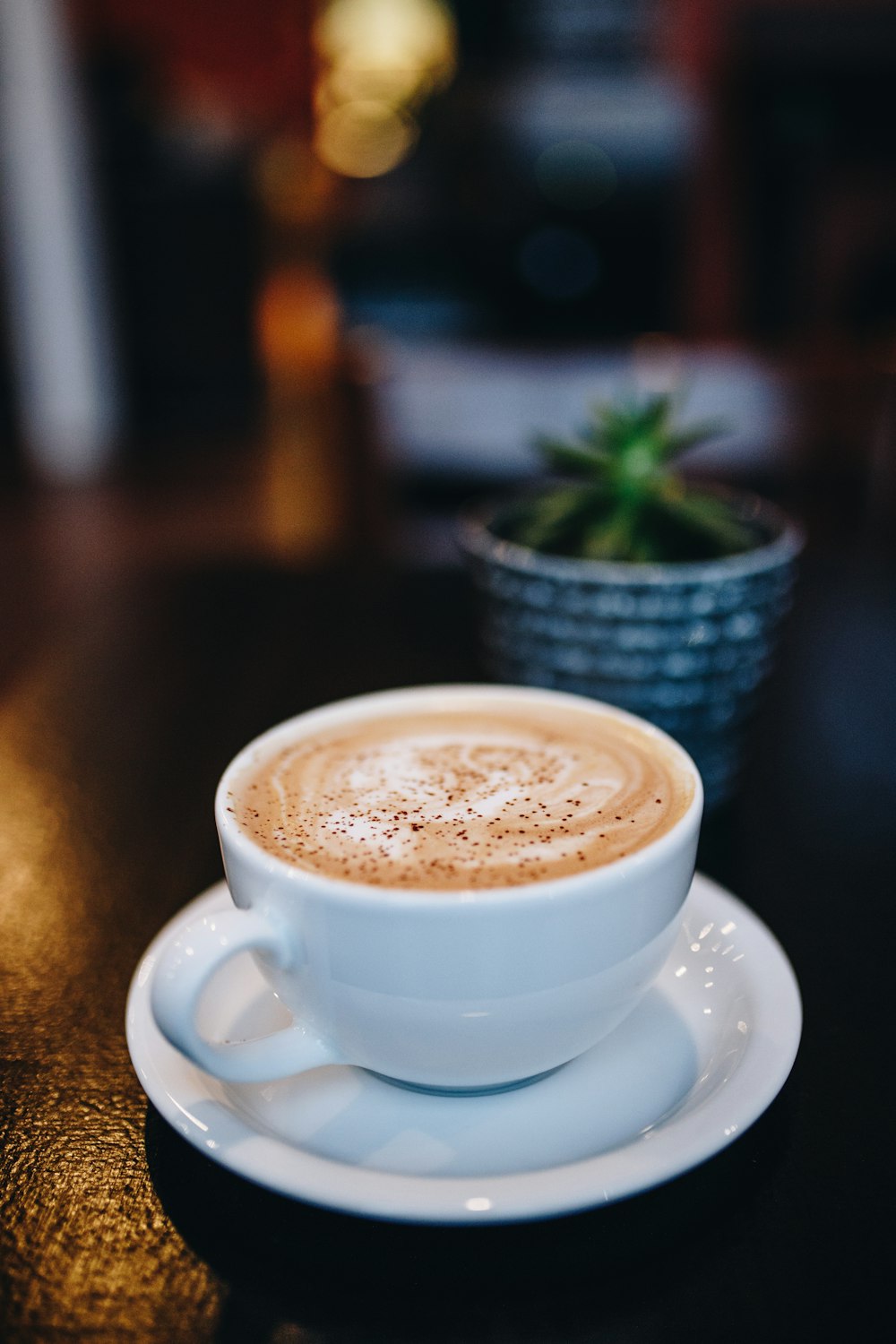 xícara de chá de cerâmica branca em pires de cerâmica branca cheia de café em foco fotografia