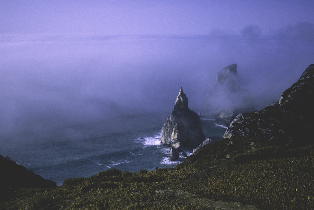 Braune Felsen, die tagsüber in Ufernähe in Nebel gehüllt sind