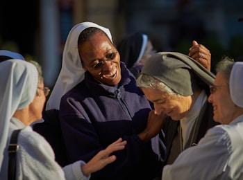 A group of nuns are gathered together, smiling and engaging in conversation. They appear to be enjoying each other's company, sharing a moment of joy and camaraderie. The setting suggests a sense of community and friendship.