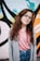 girl wearing eyeglasses with silver frames behind graffiti