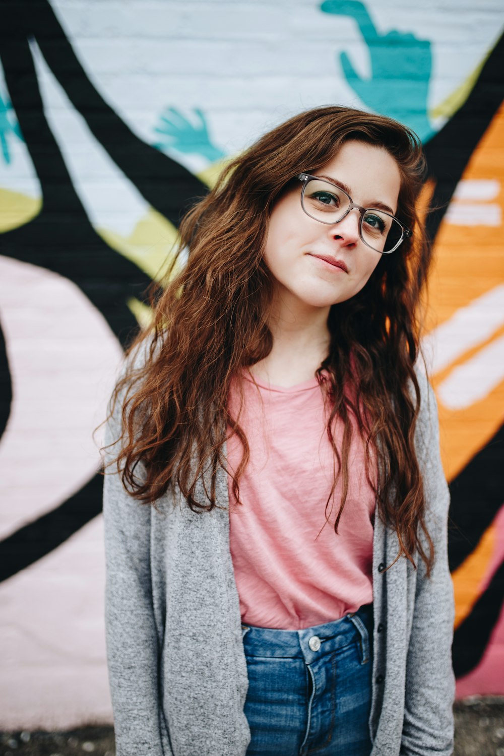 girl wearing eyeglasses with silver frames behind graffiti