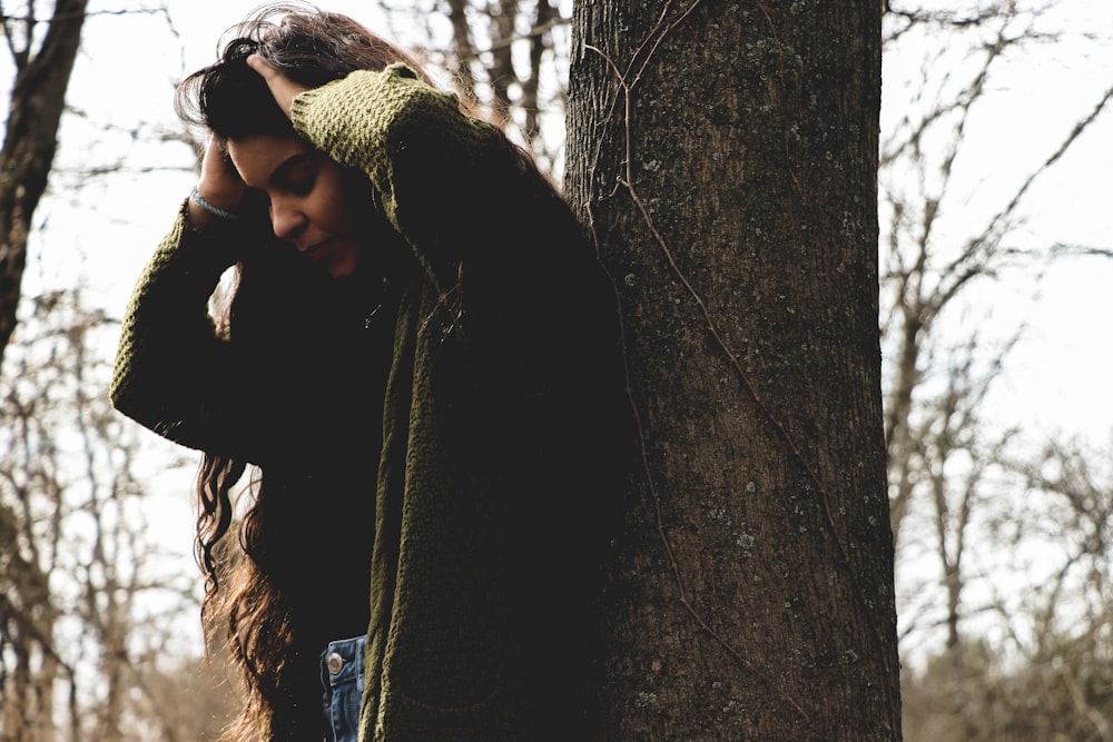 woman leaning on tree trunk