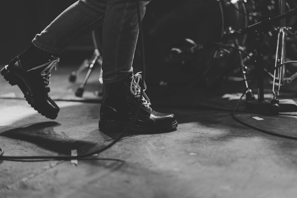 person in black leather boots walking beside of drum set