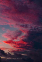 A dramatic sky at twilight with glowing streaks of light weaving through dark clouds.