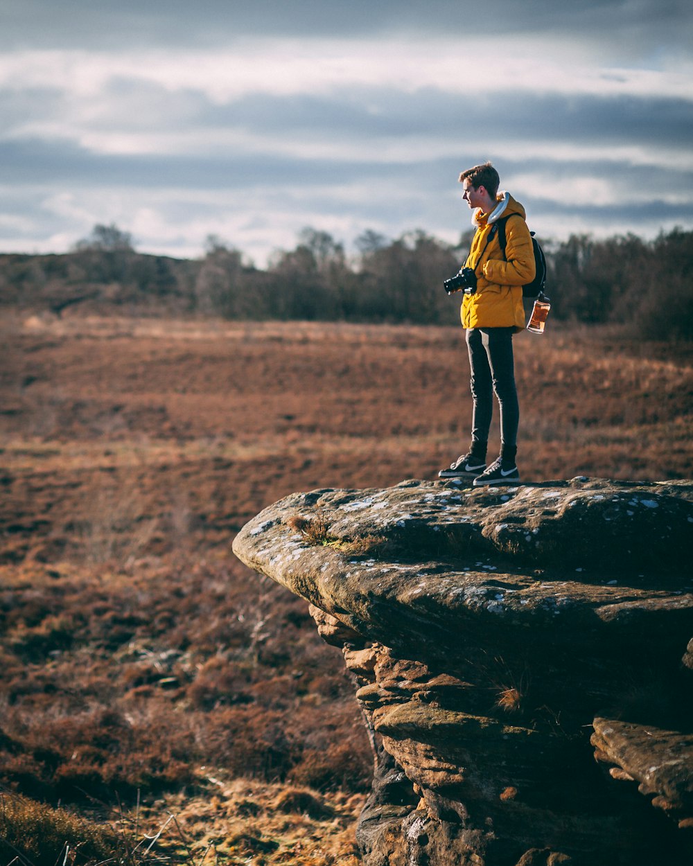 man standing at cliff holding his camera