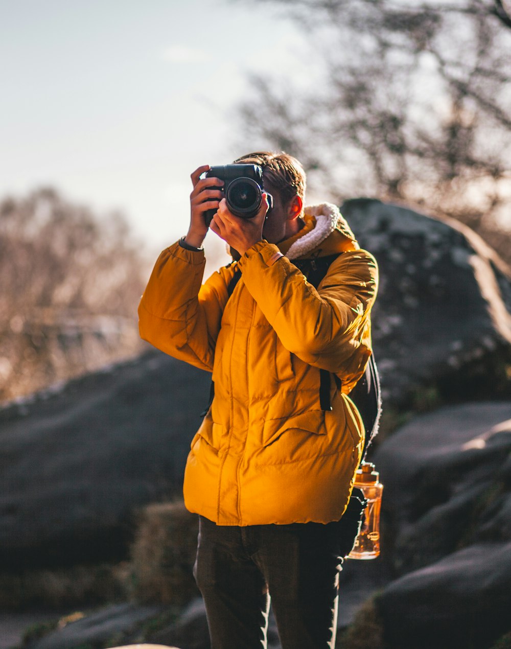 man taking picture near gray rock