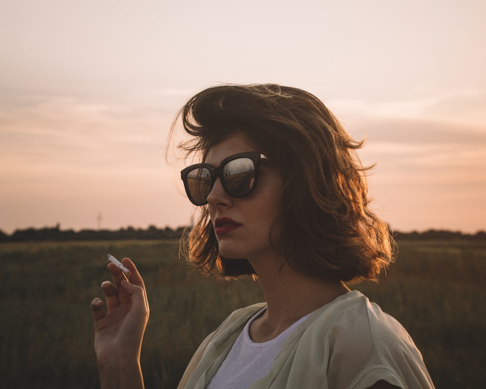 fotografía de enfoque selectivo de mujer sosteniendo un cigarrillo