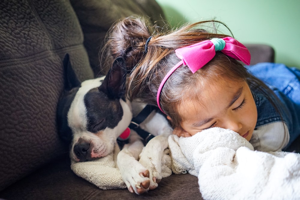 menina que dorme ao lado de um cachorro no sofá